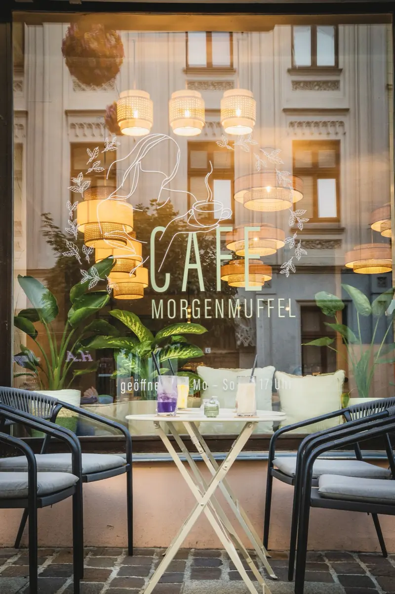 Blick durchs Schaufenster auf Rattanlampen, Pflanzen und Fensterplätze
