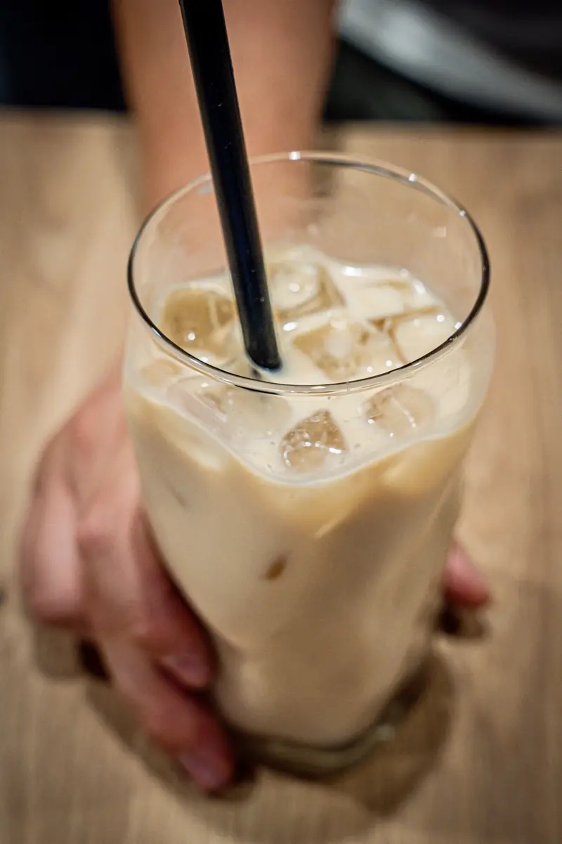 Eiskalter Latte im Glas, von einer Hand gehalten