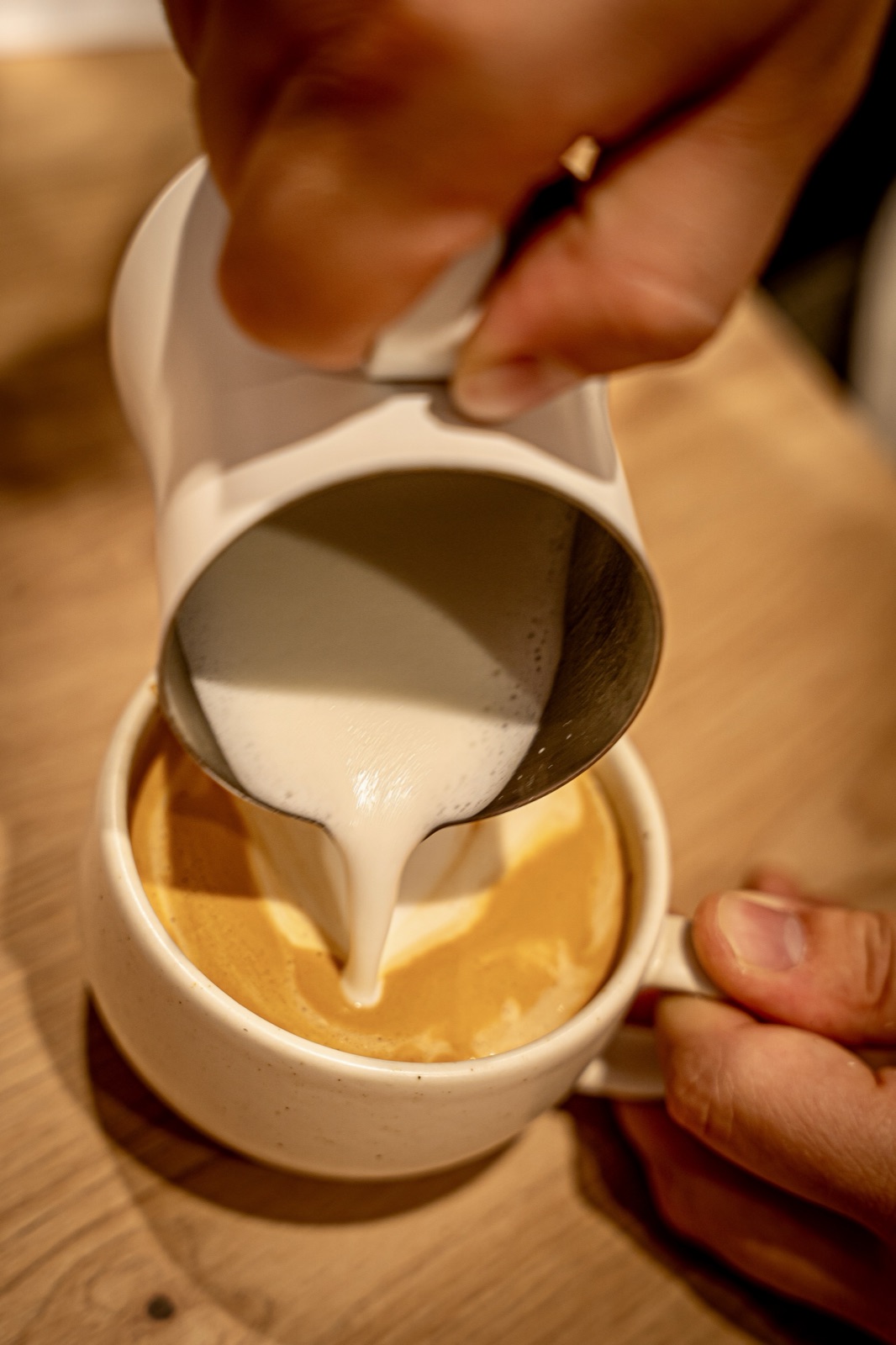 Latte Art wird in eine Tasse gegossen im Café Morgenmuffel